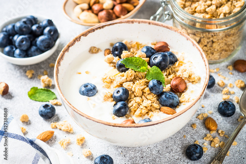 Yogurt with granola and fresh berries at white table. Healthy food, snack or breakfast.