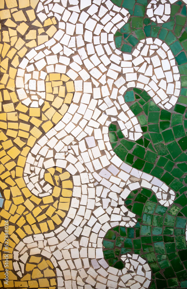 Obraz premium Detail of a beautiful abstract decoration of a building decorated with wave-shaped ceramic mosaics. Venetian mosaic as a decorative background. Mosaic ceramic stones for decorating pool walls.