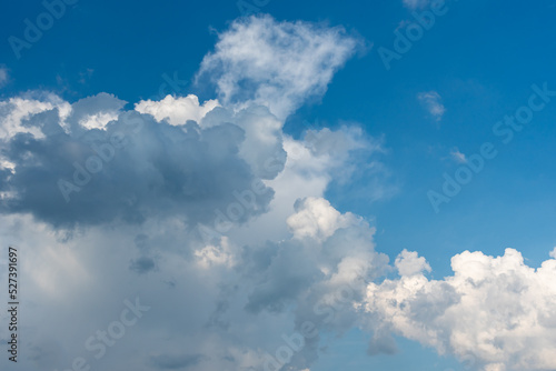 Illuminated cumulus white clouds against a blue sky.