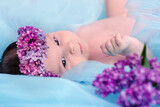 baby with lilac flowers. Happy laughing baby in flowers.