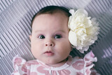 Little pretty girl with brown eyes with peony flowers. Happy laughing baby in flowers.