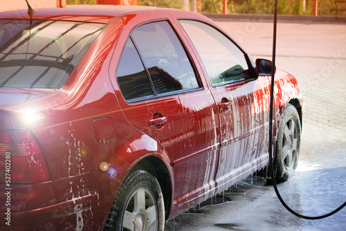 Rinsing a car at a self-service car wash in the summer