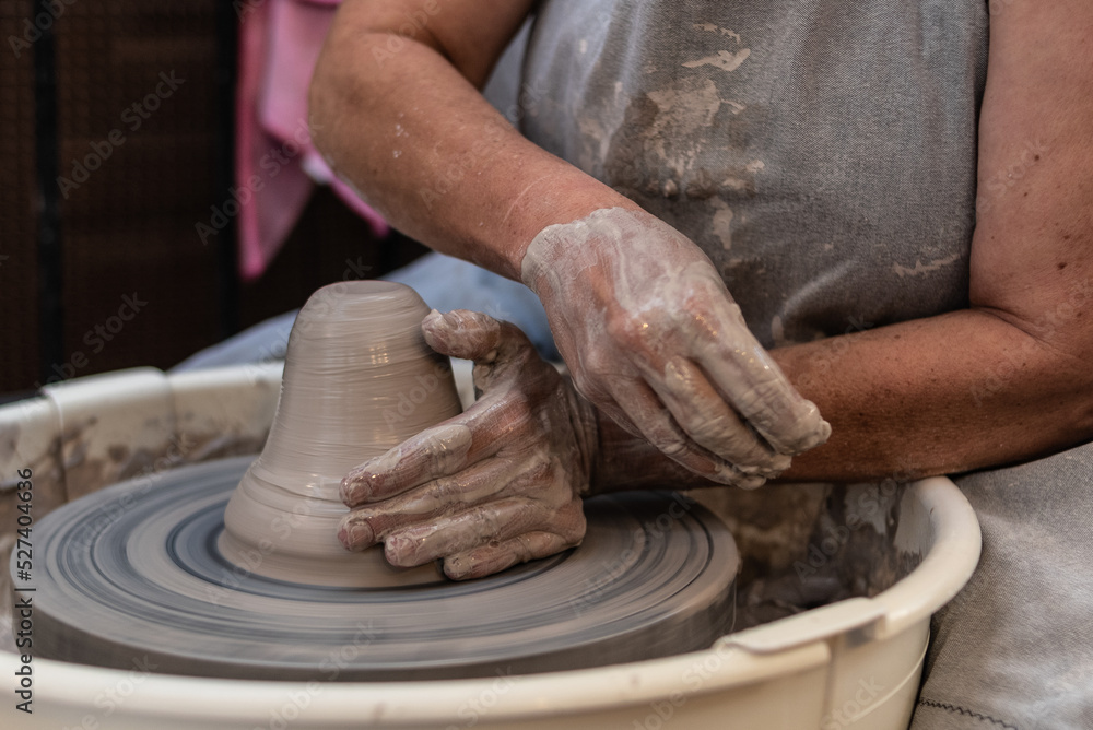 hands working a piece of clay on the potter's wheel