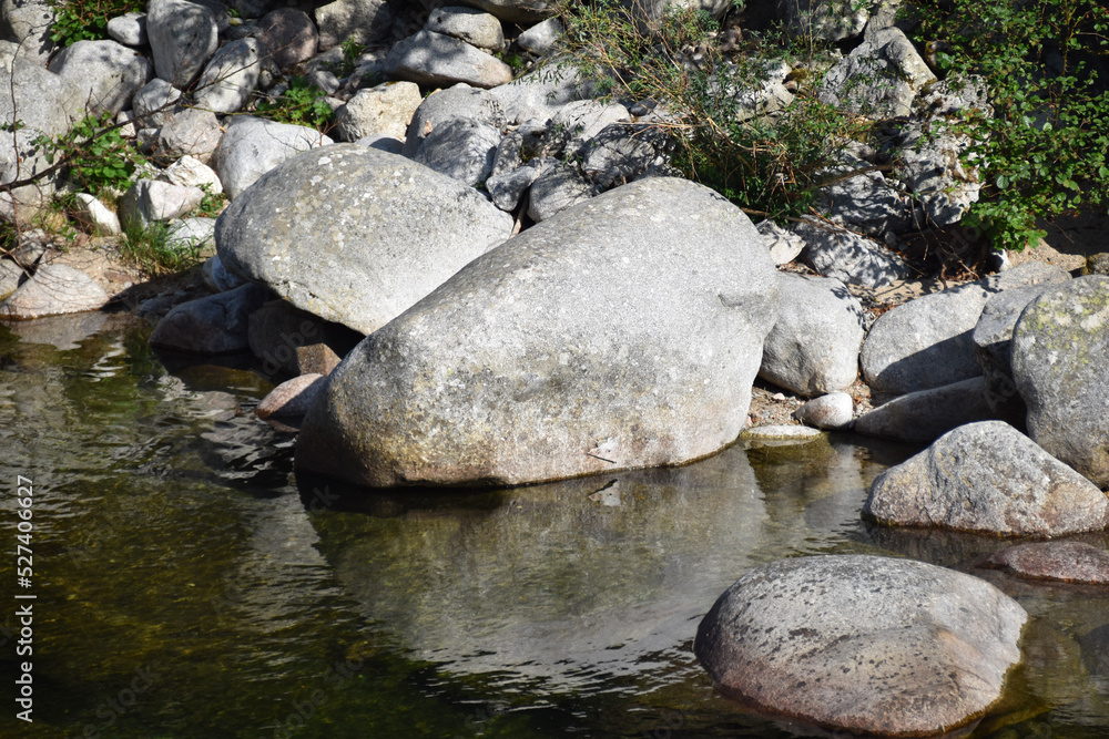 Große Felsen und kleine Steine liegen in einem Fluss und bilden einen kleinen See Große Felsen und kleine Steine liegen in einem Fluss und bilden einen kleinen See