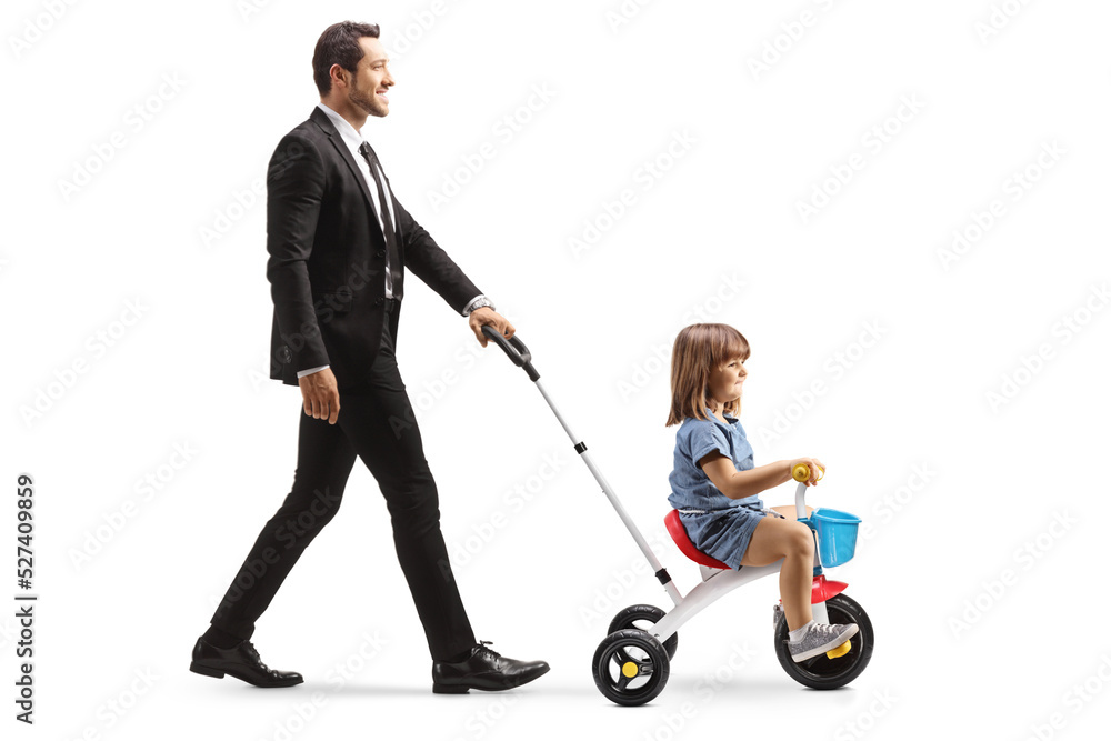 Profile shot of a man pushing a little girl on a tricycle Profile shot of a man pushing a little girl on a tricycle
