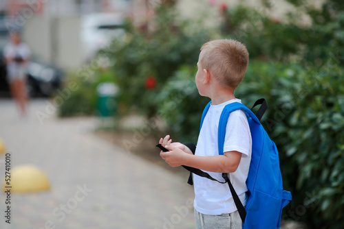 A boy with a briefcase on his back goes to school. Back to school. Safe road to school.