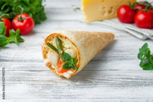 pizza in a cone cheese, fish and vegetables on white wooden table