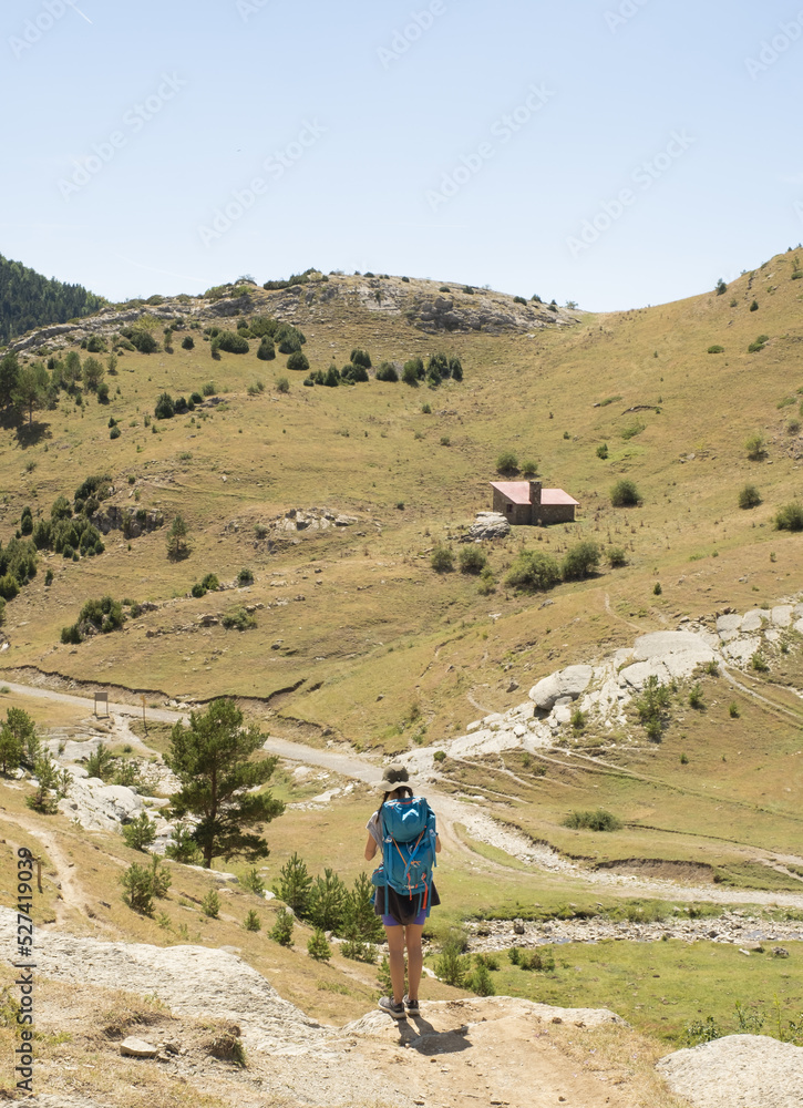 Girl with backpack walks towards the refuge in the Iguer cirque, Western Valleys Natural Park, Huesca.