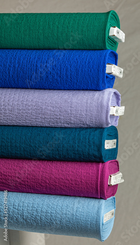 Stack of colorful fabric bolts | Pile of blue, green, and pink cloth