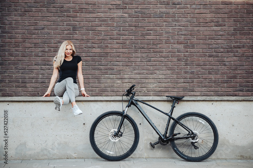 Happy smilling woman sitting near bike after morning cycling