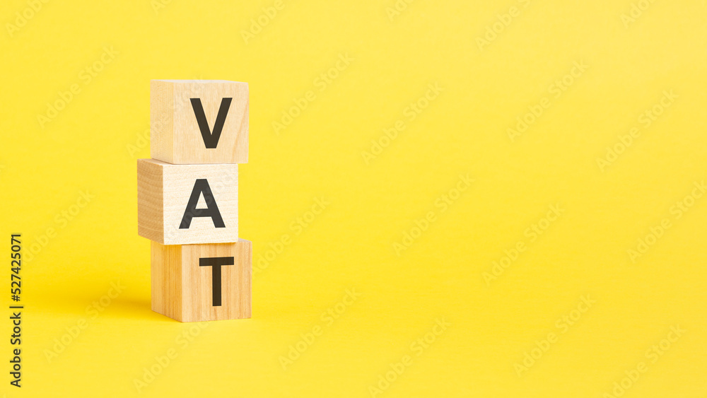 VAT - Value Added Tax - text on wooden block with yellow background. VAT - Value Added Tax - text on wooden block with yellow background.