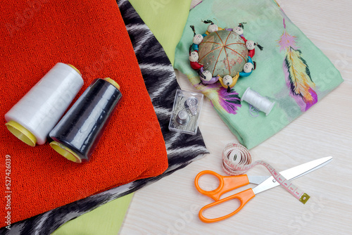 Fabric, scissors and various sewing supplies on a wooden table close-up