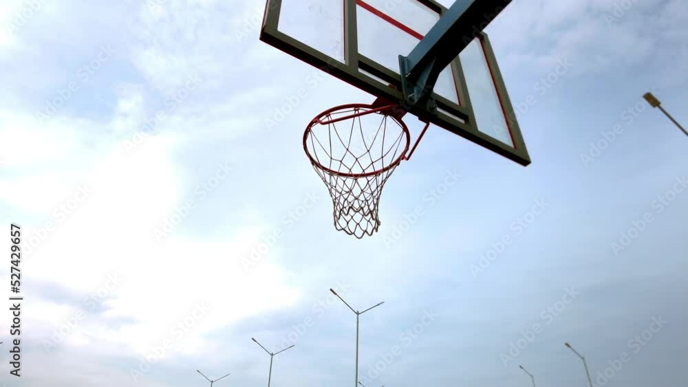 Practice on an outdoor athletic field to throw the ball into a basketball hoop, camera tracking, sky background Practice on an outdoor athletic field to throw the ball into a basketball hoop, camera tracking, sky background