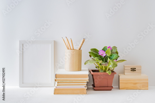 Mockup with a white frame  flowers in a pot on a light background. Empty poster frame mockup for presentation design  text  lettering