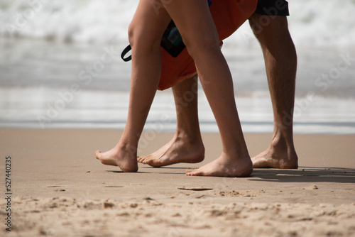 two people walking on the sand by the sea