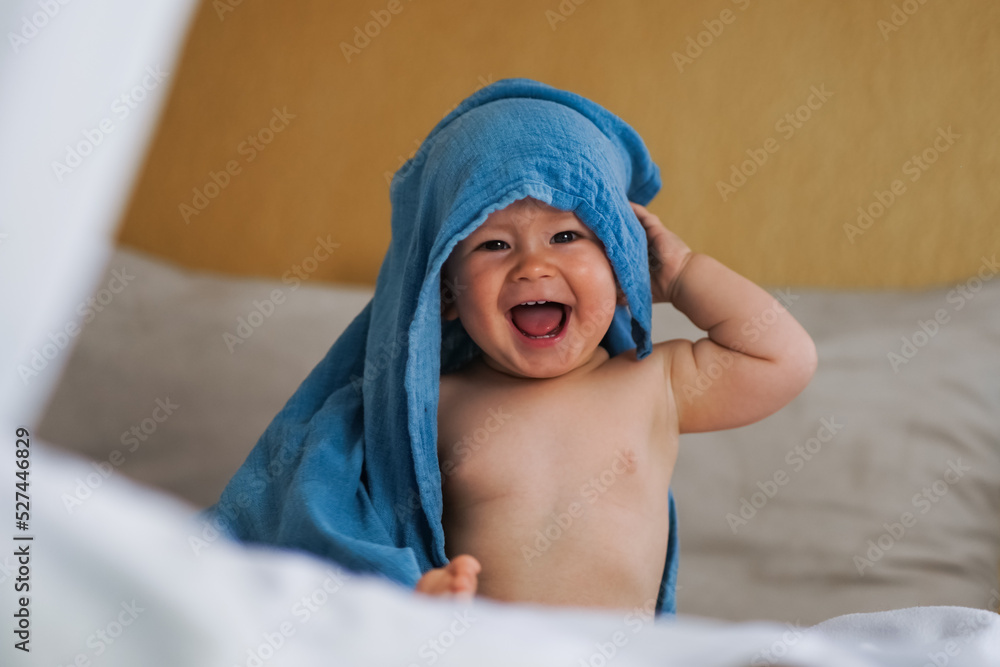 mega cute naked almost one year old blond baby boy sitting & laughing at home on a cozy bed after bathing and playing with a blue muslin fabric burp cloth while making nonsense jokes mega cute naked almost one year old blond baby boy sitting & laughing at home on a cozy bed after bathing and playing with a blue muslin fabric burp cloth while making nonsense jokes