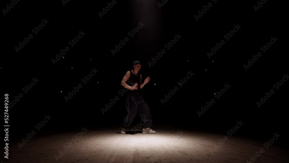 teen boy is dancing hip-hop and breakdance in darkness in spotlight ray, active dance and freestyle teen boy is dancing hip-hop and breakdance in darkness in spotlight ray, active dance and freestyle