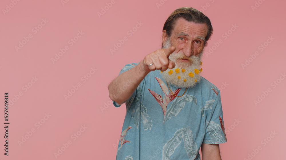 Hey you. Senior man with flowers in beard smiling excitedly and pointing to camera, choosing lucky lottery winner, indicating to awesome you. Elderly grandfather isolated on pink studio background Hey you. Senior man with flowers in beard smiling excitedly and pointing to camera, choosing lucky lottery winner, indicating to awesome you. Elderly grandfather isolated on pink studio background
