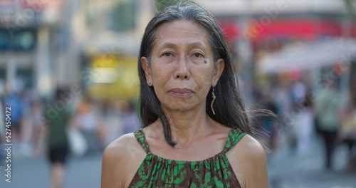 Mature Asian woman serious angry sad face portrait on city street © blvdone