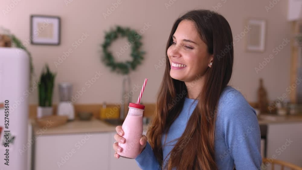 Happy young woman drinking strawberry smoothie in the kitchen. Healthy lifestyle concept. High quality 4k footage Happy young woman drinking strawberry smoothie in the kitchen. Healthy lifestyle concept. High quality 4k footage