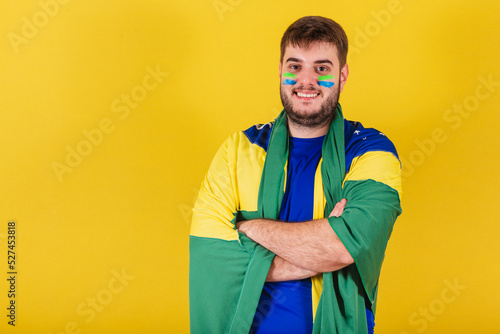 caucasian brazilian man, brazil soccer fan, arms crossed, wearing brazil flag cape.
