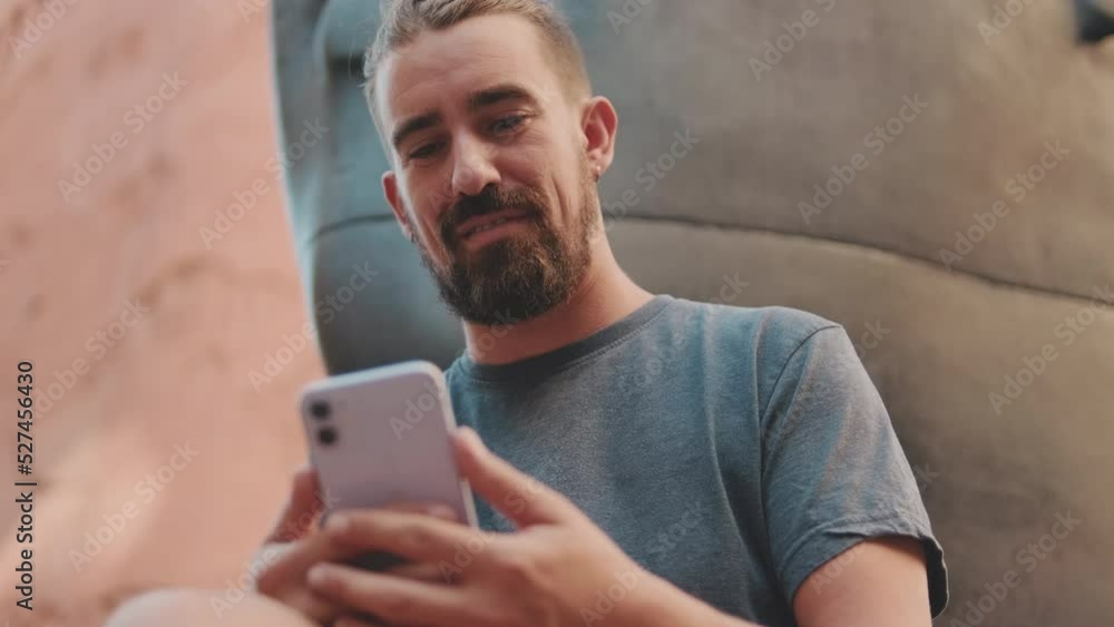 Young adult man with beard uses phone outside Young adult man with beard uses phone outside