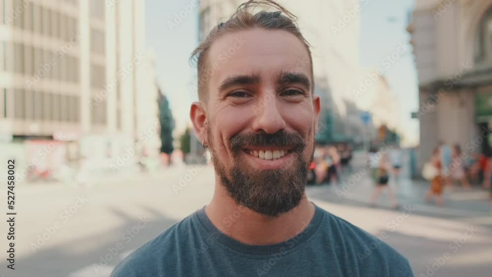 Portrait of young smiling man with beard standing in front of busy intersection Portrait of young smiling man with beard standing in front of busy intersection