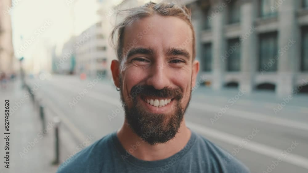 Portrait of young man with beard looking and smiling at the camera Portrait of young man with beard looking and smiling at the camera