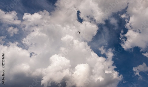The plane in the sky is flying under the clouds