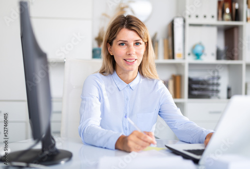 Office manager works with documents and laptop in office