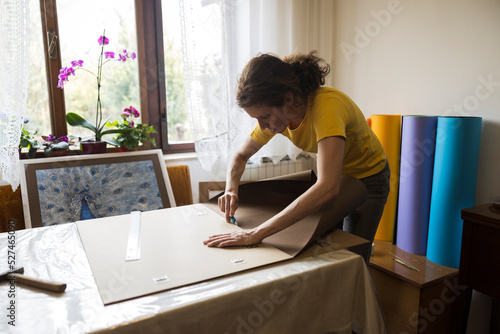 Mid Adult Female Artist Wallpapering and Framing Pictures and Photos in Her Domestic Studio