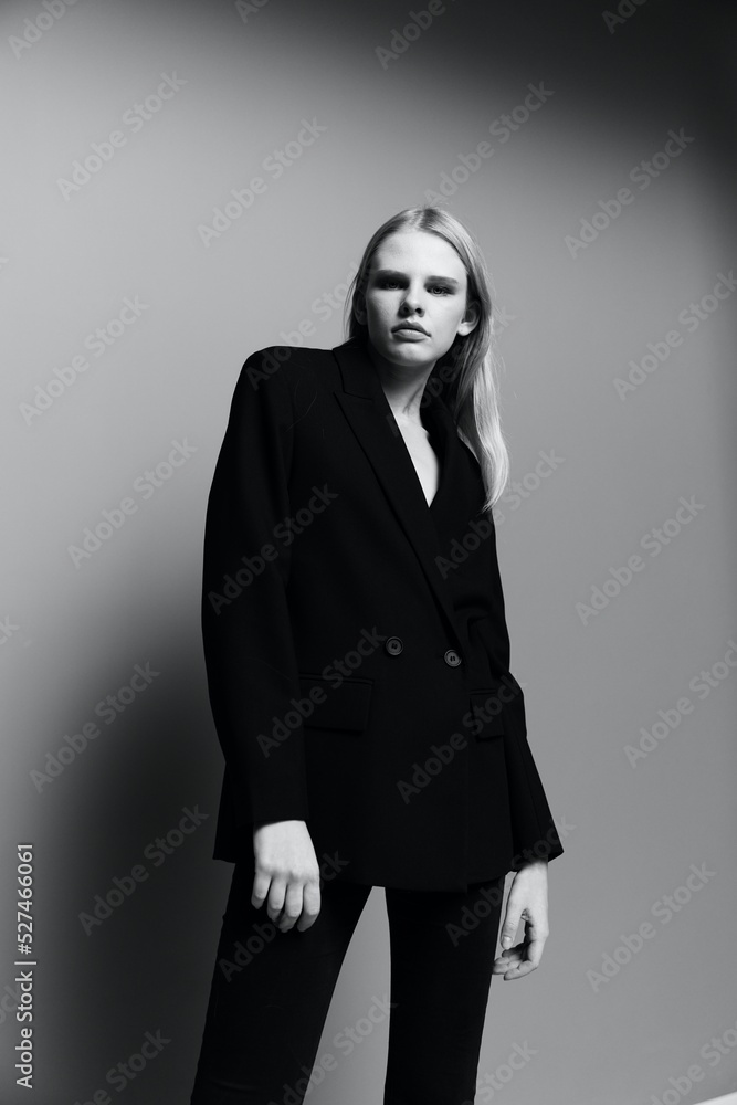 A concept for clothing brands. Cool offer banner for sale. A young lady model in a suit poses in the studio looking down into the camera A concept for clothing brands. Cool offer banner for sale. A young lady model in a suit poses in the studio looking down into the camera