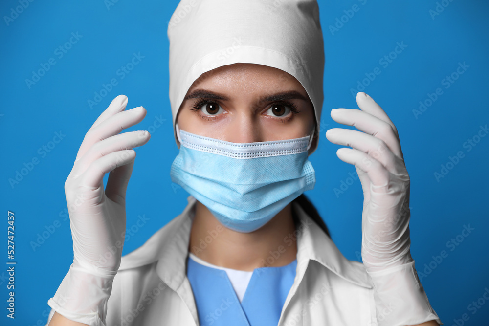 Doctor in protective mask and medical gloves against blue background Doctor in protective mask and medical gloves against blue background