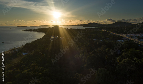 Sunrise over ko samui island from a drone capture with ocean and land mass in the frame - strong sun rays - Maenam village in Thailand