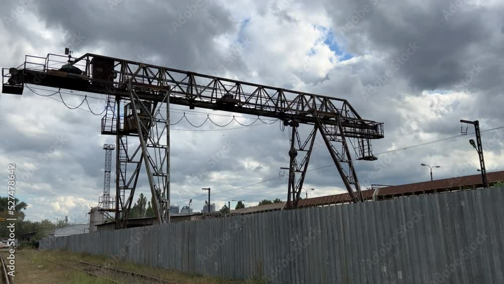 Overhead crane works in an outside storage of a scrap metal base on a cloudy day Overhead crane works in an outside storage of a scrap metal base on a cloudy day