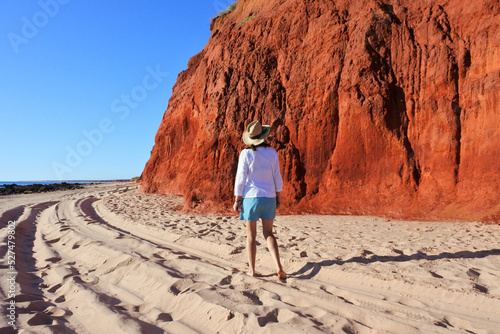 Australian woman hiking on empty beach looking at red cliff in Cape Leveque Western Australia photo
