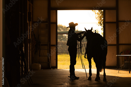 Barn alleyway silhouette tacking up horse cowboy