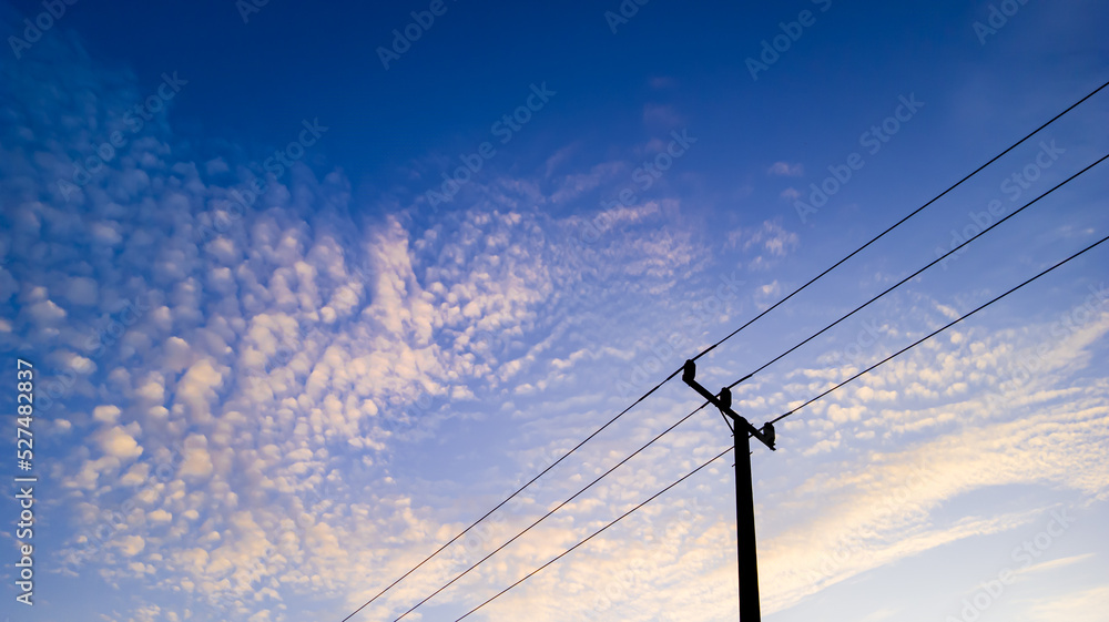 Power pole silhouette with white cloud texture in blue sky at sunrise, minimalist black electric pole on blue sky background at sunrise