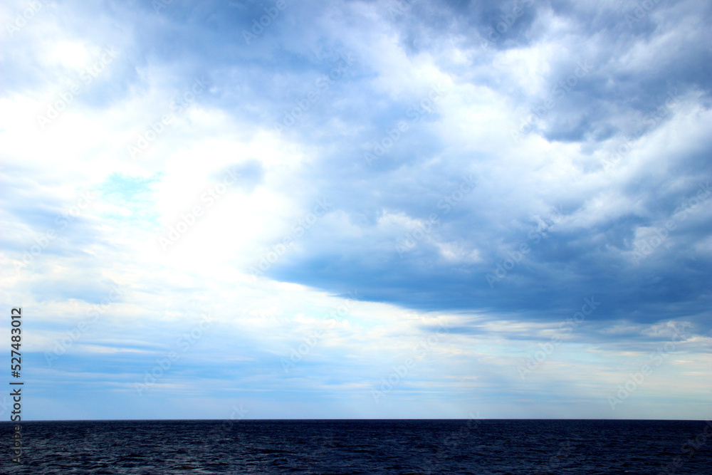 Fantastic scenery with the wavy deep blue waters of the Tyrrhenian sea standing placidly below a phenomenal sky with deep gorged clouds emitting unreal colors of blue and white on a summer day
