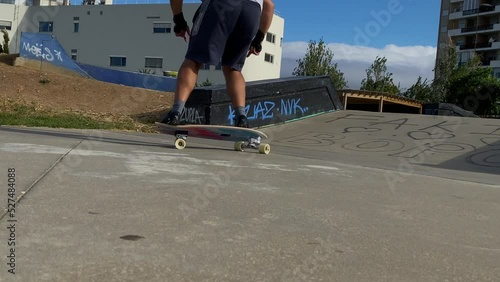 Stylish young man skateboarding doing a surf style turn around and doing some slide snaps a concrete bowl skatepark feature in a skatepark in Portugal. surf level training. Yow skate model. photo