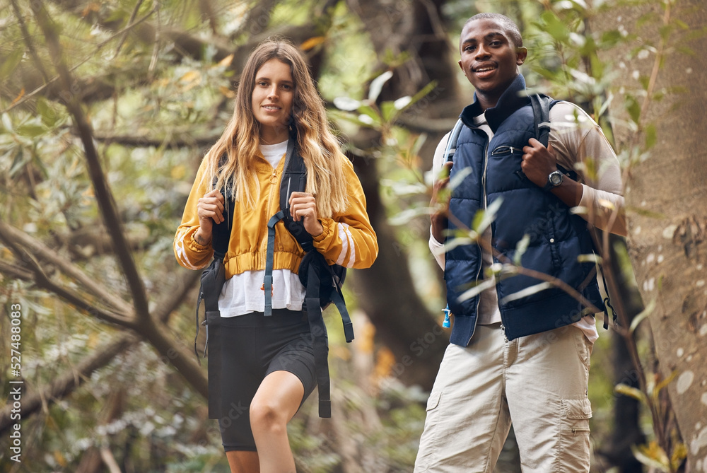 Portrait of interracial couple hiking in a nature forest environment or woods together in spring. Man and woman walking in sustainable outdoor ecology during trekking adventure or travel on holiday