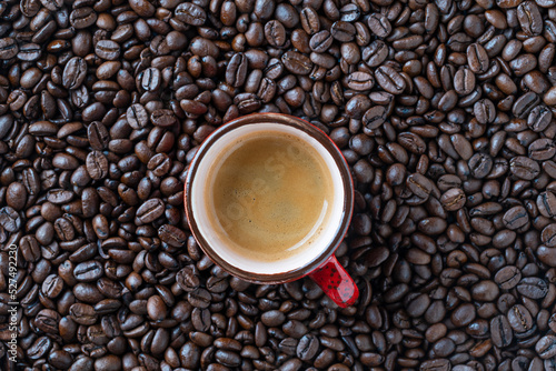 Red cup of hot coffee and background of fresh roasted coffee beans