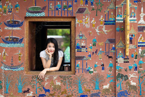 Asian woman tourist traveler at window Wat Xieng Thong temple in Luang Prabang, Laos, Wat Xieng Thong in Luang Prabang, Laos, UNESCO Town Luang Prabang World Heritage Site Wat Xieng Thong temple. photo