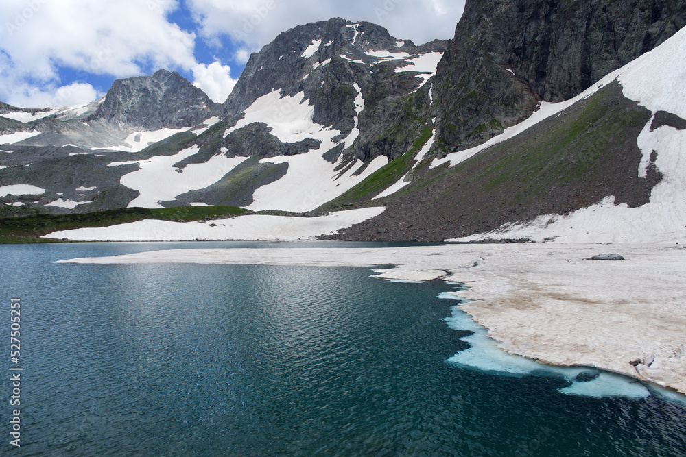 Shooting with focus stick. Mountain lake with ice floes floating in it. Mountain peaks in the background.