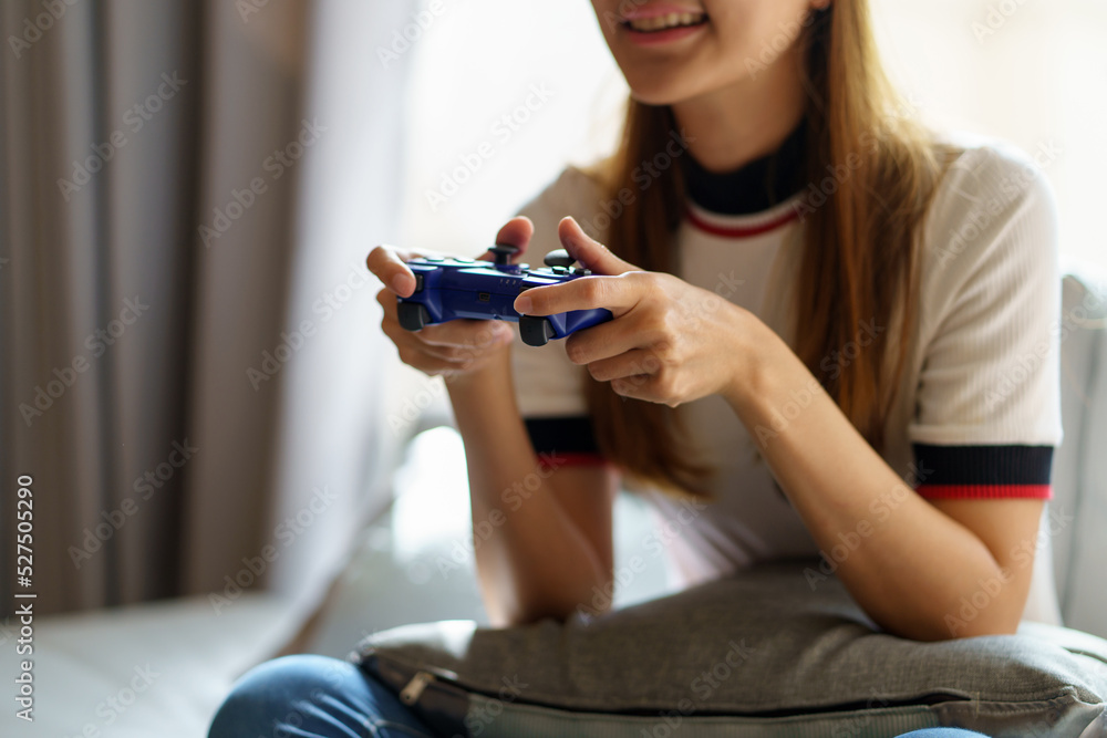 Lovely Asian woman sitting on sofa and relaxing playing games wearing VR glasses while playing games at her home with lots of fun and enjoyment. Lovely Asian woman sitting on sofa and relaxing playing games wearing VR glasses while playing games at her home with lots of fun and enjoyment.