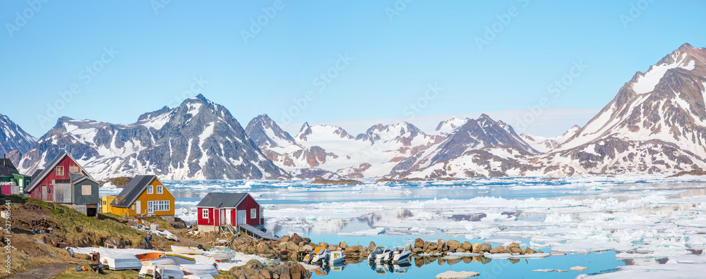 Panoramic view of colorful Kulusuk village in East Greenland - Kulusuk, Greenland - Melting of a iceberg and pouring water into the sea - obrazy, fototapety, plakaty 