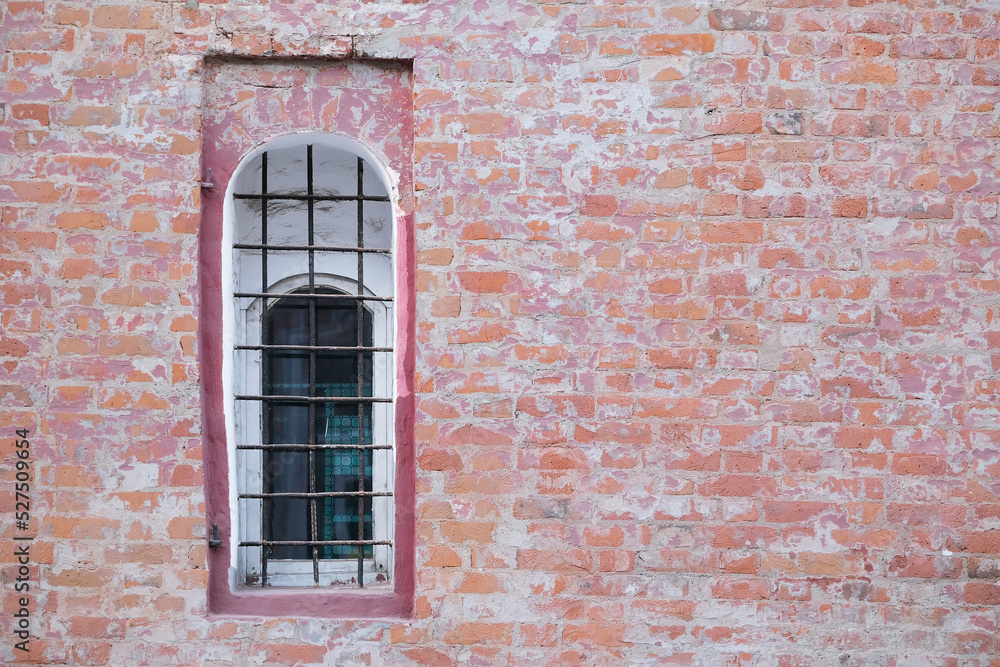 Old rough brick wall with concrete and with window with bars