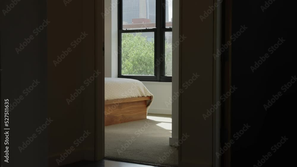 the corner of a bed from outside the room in the hallway with a window in the background the corner of a bed from outside the room in the hallway with a window in the background