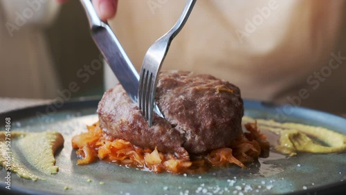 Woman eating beefcake with cabbage Bavarian style in restaurant close-up.