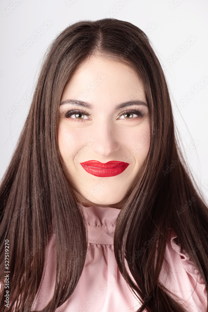 Beautiful smiling and happy woman with long dark hair and red vivid lips portrait. Model with day make-up wearing pink blouse and looking to camera with green eyes. Tones image with pink color Beautiful smiling and happy woman with long dark hair and red vivid lips portrait. Model with day make-up wearing pink blouse and looking to camera with green eyes. Tones image with pink color